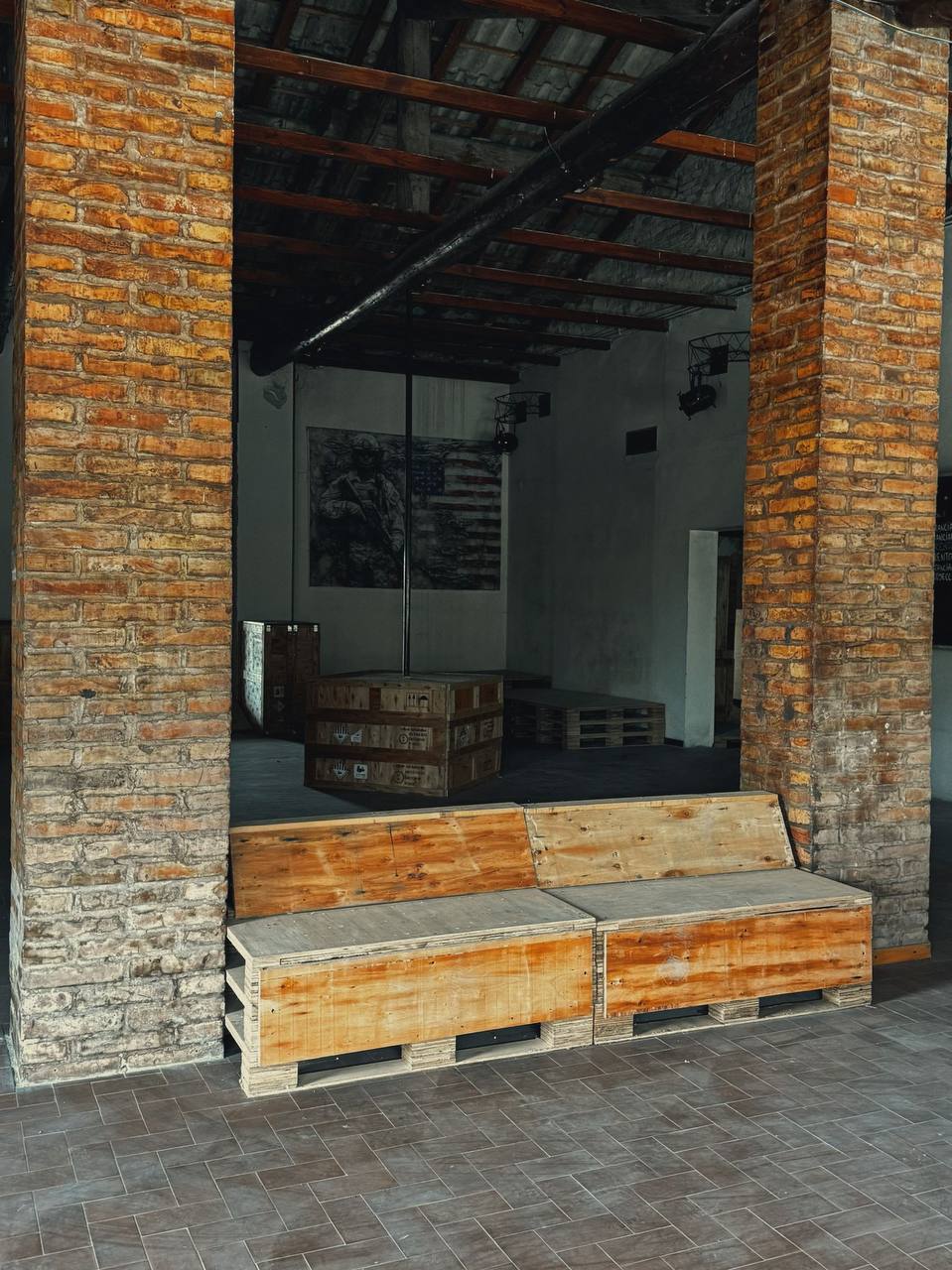 Area interna di FOX ARENA con colonne di mattoni e casse di legno